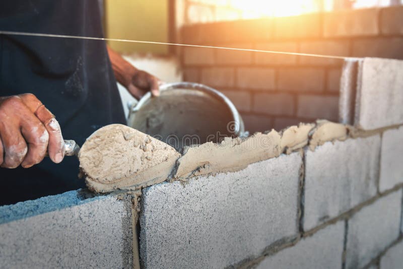 Worker building wall bricks with cement