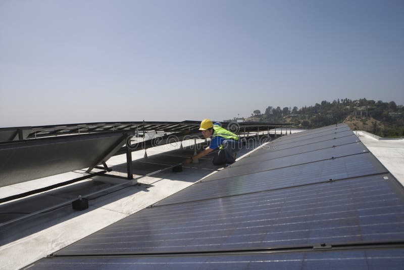 Worker Checking Solar Panels On Rooftop