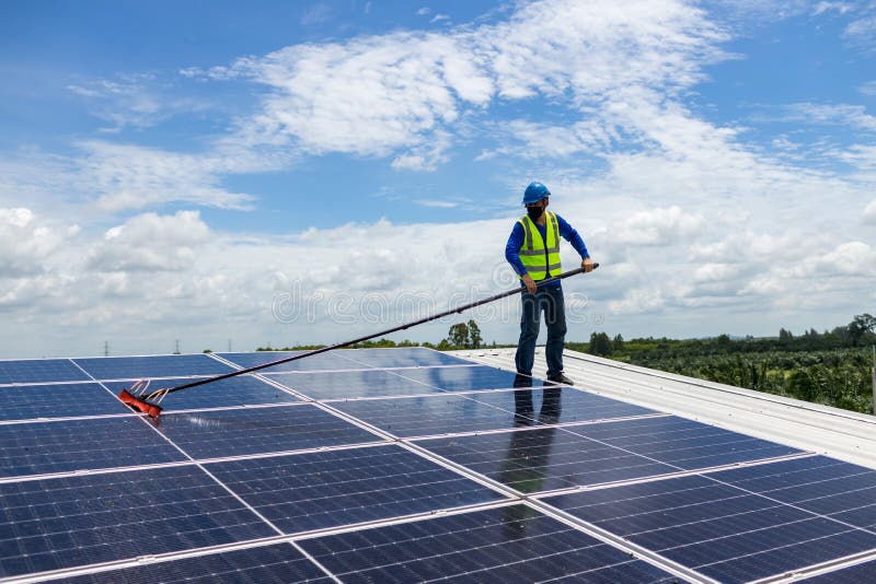 Worker Cleaning Solar Panels with Brush and Water. Worker Cleaning