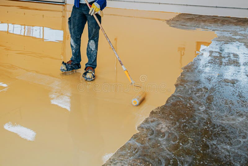 Worker, coating floor with self-leveling epoxy resin in industrial deposit royalty free stock photo
