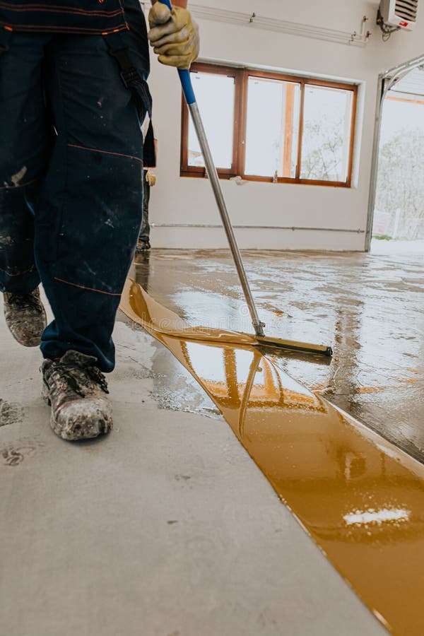 Worker, coating floor with self-leveling epoxy resin in industrial deposit royalty free stock image