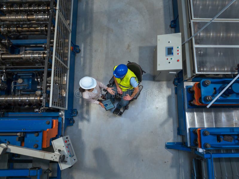 Worker consulting with a woman manager in factory, analyzing graphs on a tablet royalty free stock images
