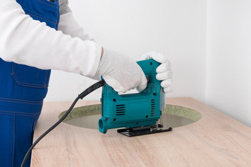 The Worker Cuts a Hole in the Countertop with a Jigsaw for Installing a Kitchen Sink Stock Image