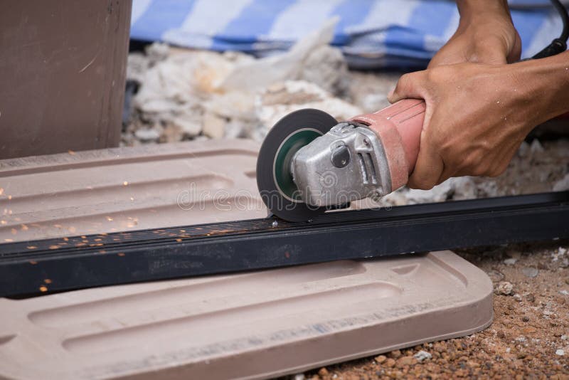 Worker Cutting Aluminum Plate with Electrical Wheel Grinder Stock Image