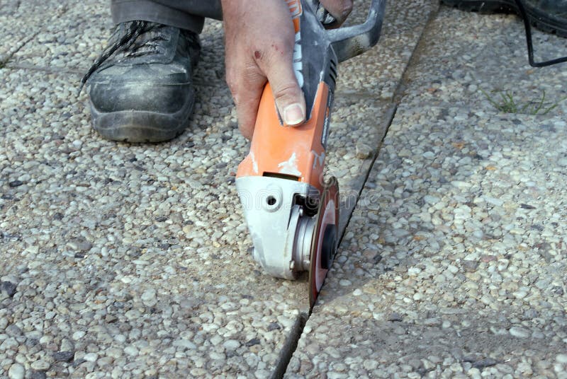 Worker Cutting Concrete Tile with Electric Hand Saw. Stock Photo
