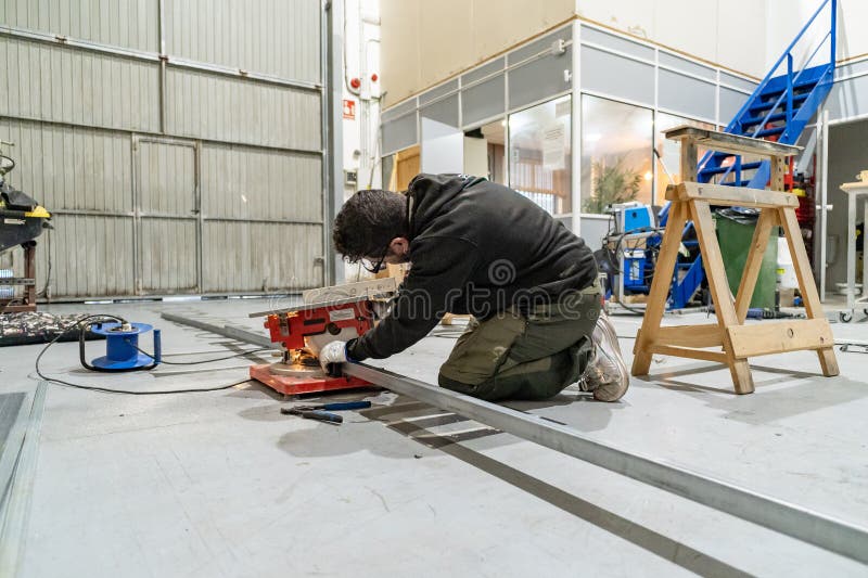 Worker cutting metal profile using miter saw in workshop stock photography