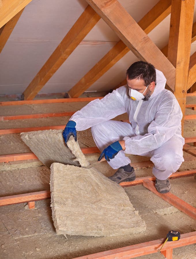 Worker cutting mineral wool panel to install thermal insulation stock photos
