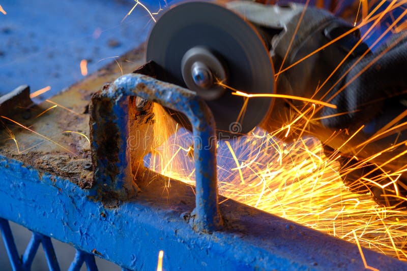 Worker Cutting Steel with Grinding Machine and Splashes of Sparks in