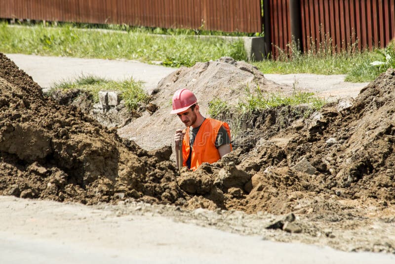 Worker digging a trench for sewer stock photography