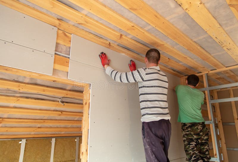 A worker fastens a sheet of drywall to the wall royalty free stock image A worker fastens a sheet of drywall to the wall royalty free stock image