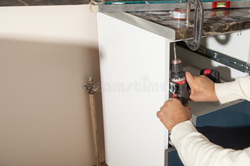 Worker Fixing Kitchen Using Cordless Screwdriver Stock Photo