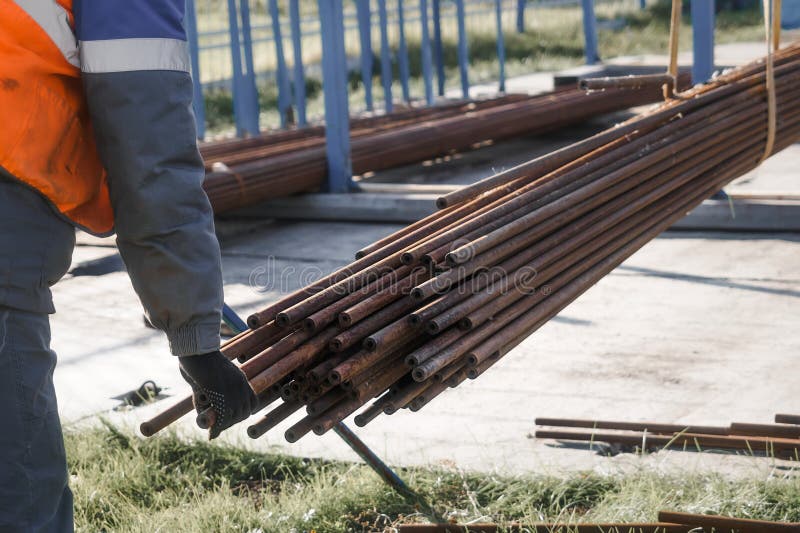 Worker handling metal pipes on industrial construction site outdoors stock photo