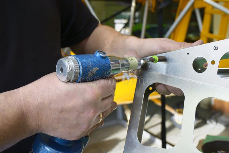 Worker hands making holes with a drill on the body plane for further riveting, planes assembly hall royalty free stock photo