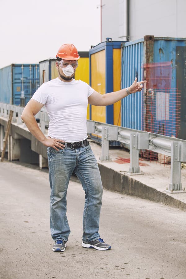 Pracovník v prilbu a ochrannú masku stojí na obaloch nebezpečných odpadov alebo látok.