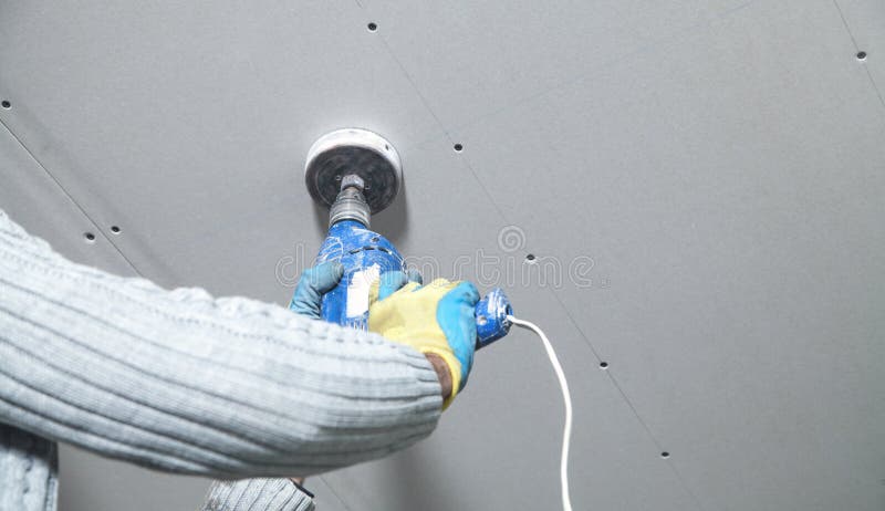 Worker Holding A Power Drill Make A Hole In The Ceiling Install