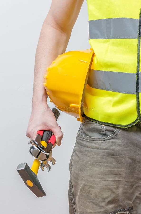 Worker holds yellow helmet, hammer and other tools royalty free stock photography