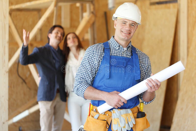 Worker holding house design plans and a young couple at construction site. Worker holding house design plans and a young couple at construction site