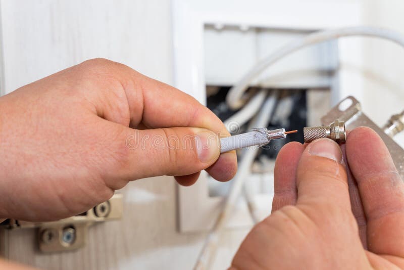 Worker Inserts Connector of a TV Antenna Coaxial Cable. Stock Photo