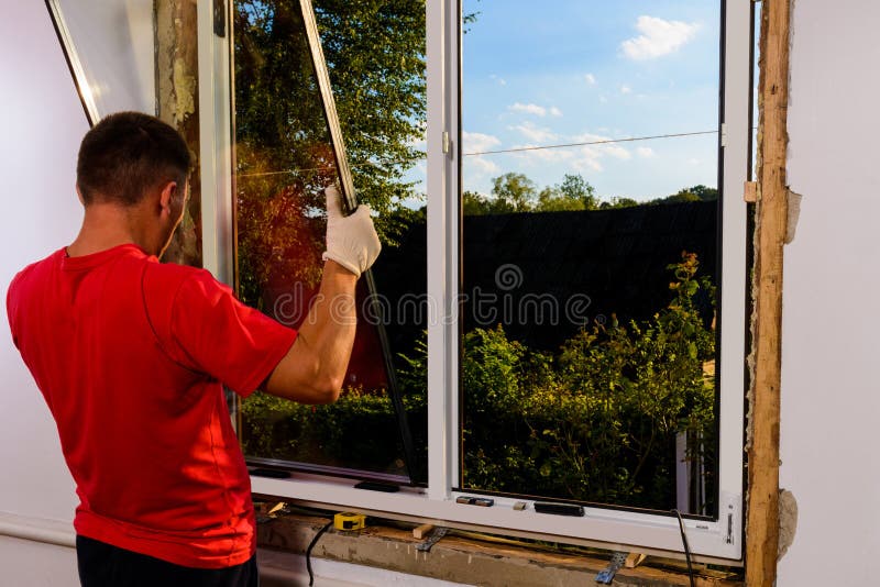 Window Installation Worker Inserts Glass into the Frame and Fastens it ...