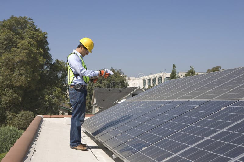 Worker Inspecting Solar Panels On Rooftop