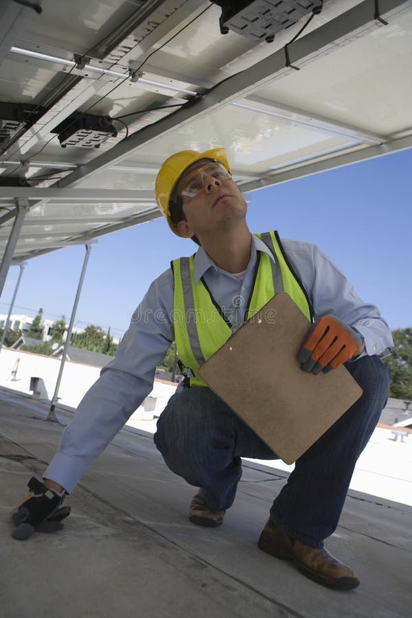 Worker Inspecting Solar Panels On Rooftop