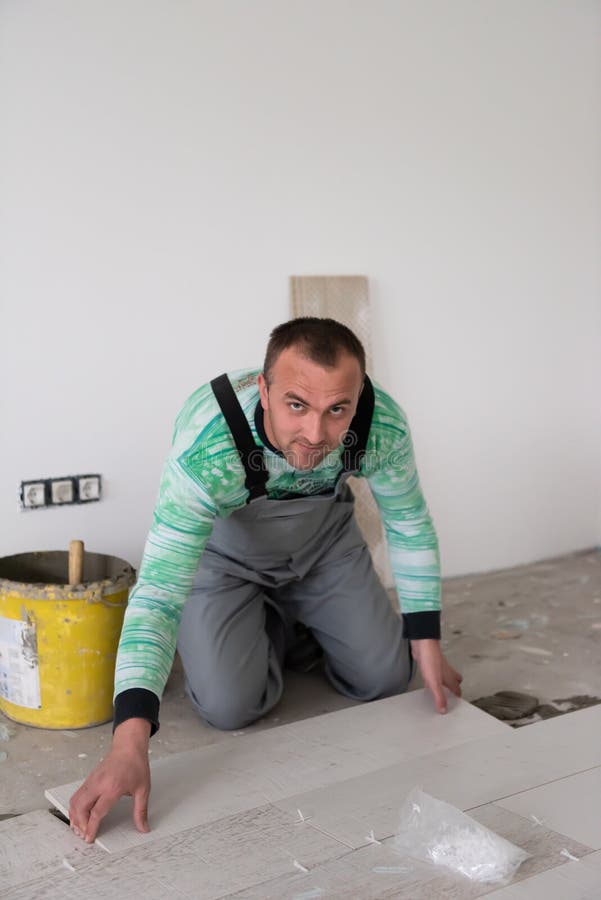 Worker Installing the Ceramic Wood Effect Tiles on the Floor Stock