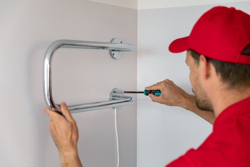 Worker installing electric towel dryer on the bathroom wall stock image Worker installing electric towel dryer on the bathroom wall stock image