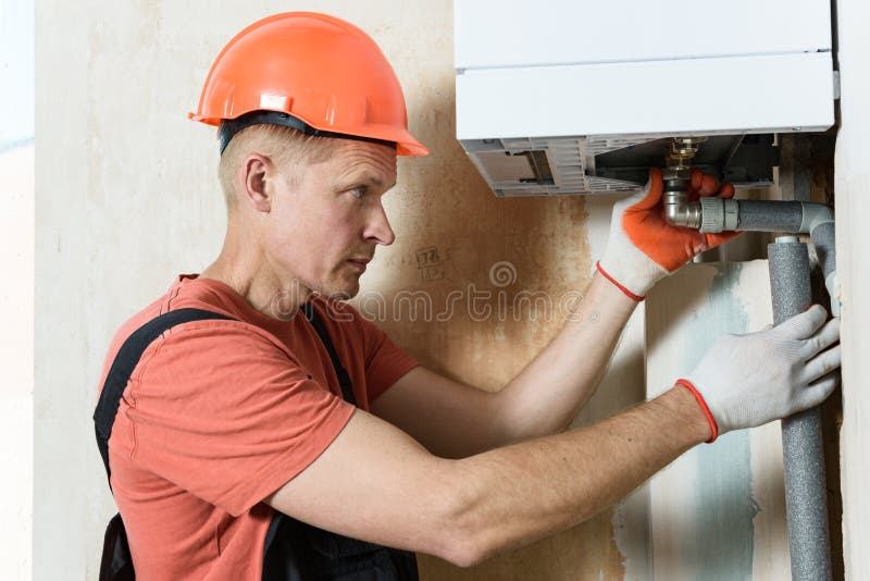 The worker is installing the gas boiler pipes
