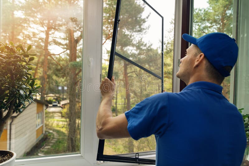 Worker installing mosquito net wire screen on house window royalty free stock photos