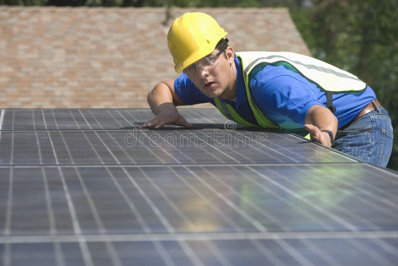 Worker Installing Solar Panels On Rooftop