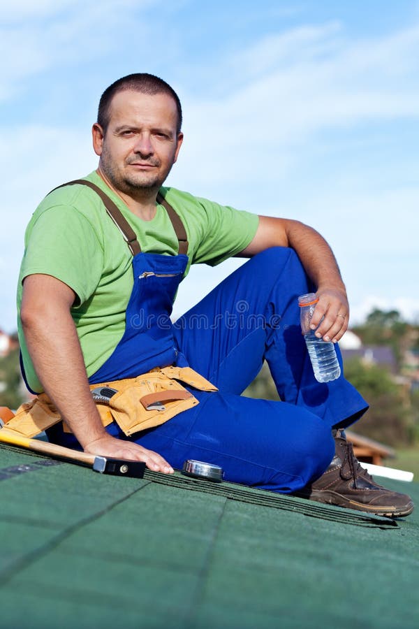 Worker laying bitumen roof shingles stock photo