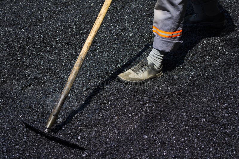 Worker leveling fresh asphalt on a road construction site, indus royalty free stock images Worker leveling fresh asphalt on a road construction site, indus royalty free stock images