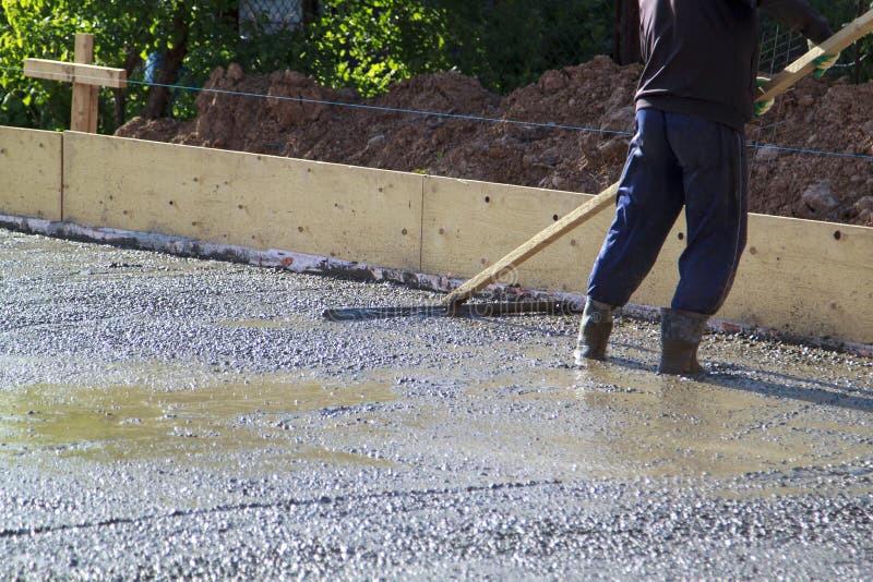 Worker leveling fresh concrete slab with a special working tool stock images