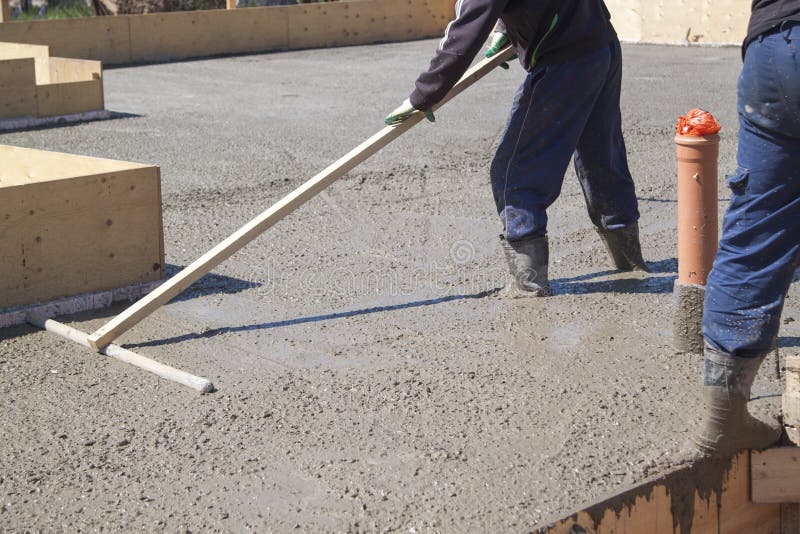 Worker leveling fresh concrete slab with a special working tool stock photos