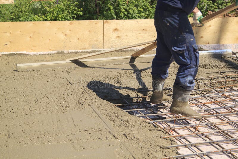 Worker leveling fresh concrete slab with a special working tool stock photography