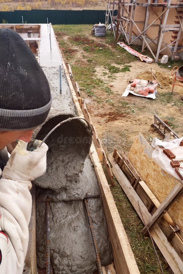 Worker Lines Concrete in Formwork with Trowel, Construction of New Home