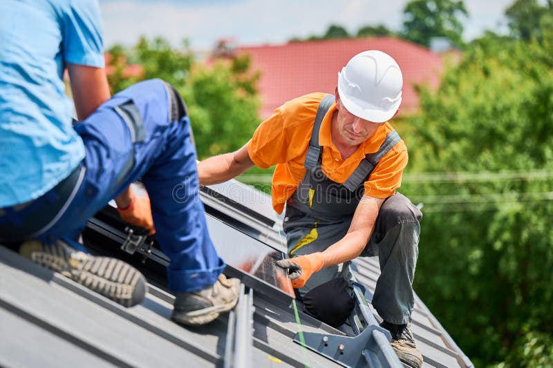 Worker looking on evenness of solar modules while building photovoltaic solar system on roof. stock images