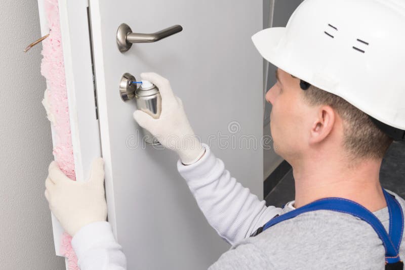 A Worker Lubricates the Closing Mechanism of the Lock on the Door with