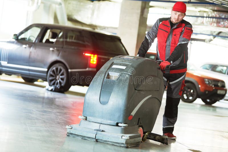 Worker with Machine Cleaning Floor in Parking Garage. Stock Image