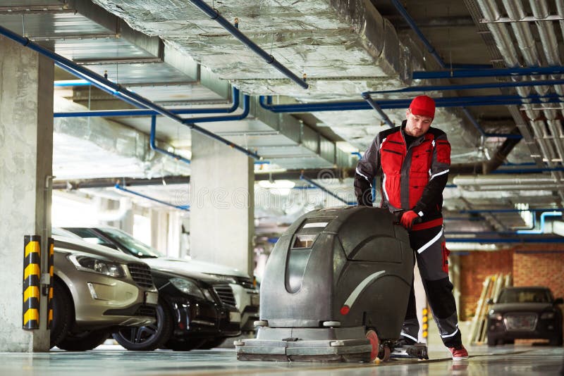Worker with Machine Cleaning Floor in Parking Garage. Stock Image