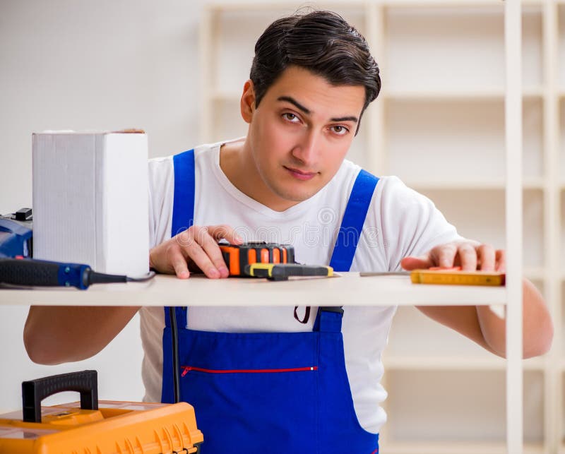 Worker man repairing assembling bookshelf royalty free stock photography