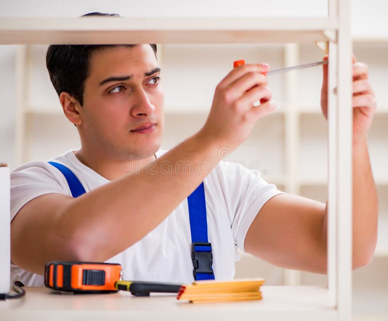 Worker man repairing assembling bookshelf royalty free stock images