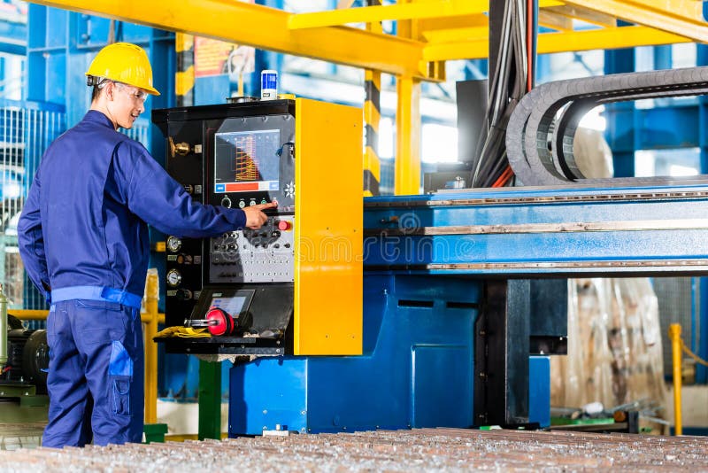 Worker in manufacturing plant at machine control panel