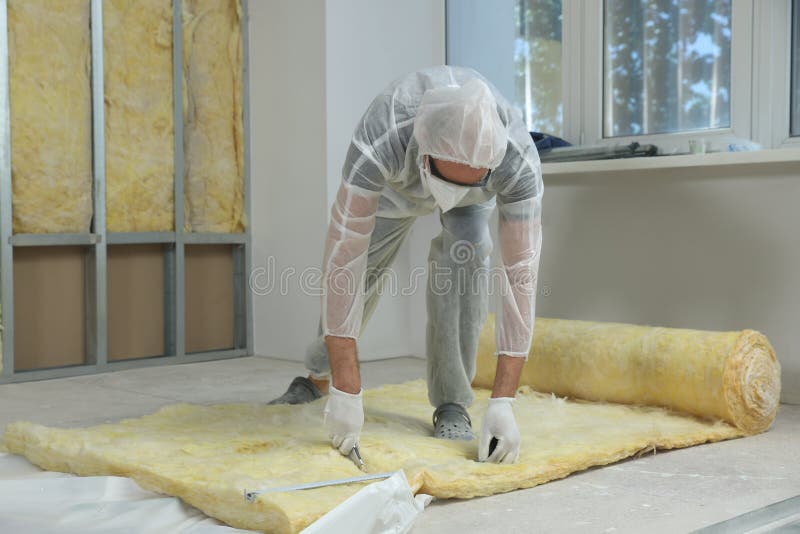 Worker measuring and cutting insulation material indoors stock images