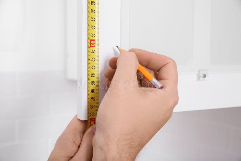 Worker measuring newly installed kitchen furniture stock images