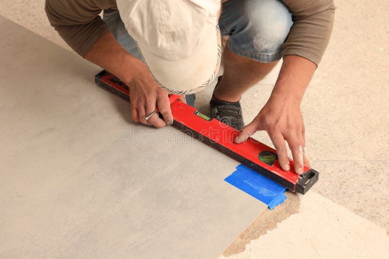 Worker measuring tile with building level indoors royalty free stock images