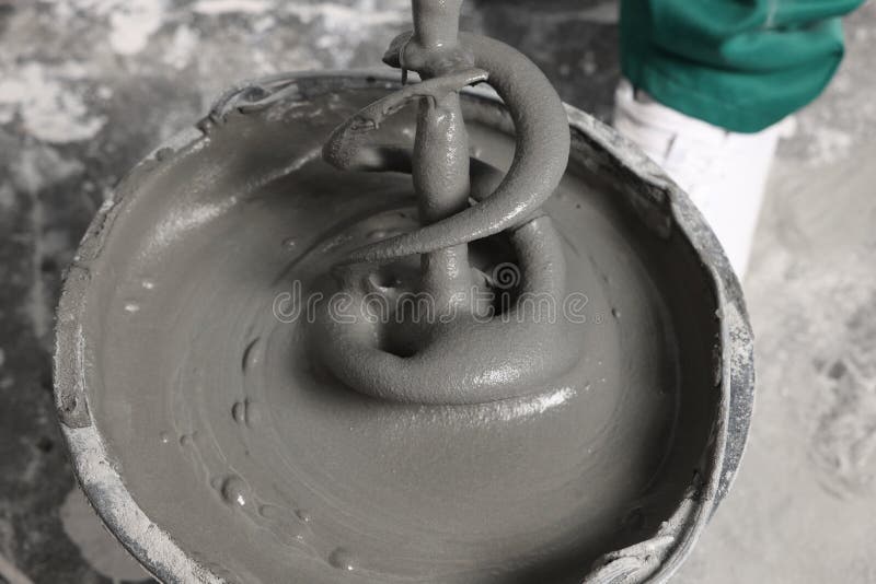 Worker Mixing Concrete in Bucket Indoors, Closeup Stock Photo Image