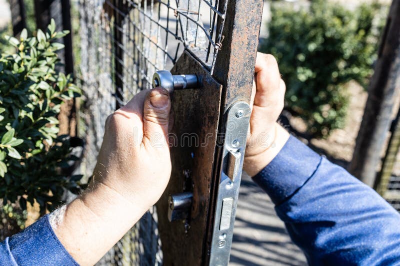 Worker Mounts New Door Lock in Iron Gate Close Up Stock Photo - Image ...