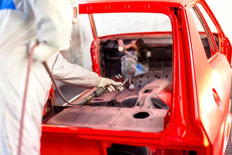 Worker Painting a Red Car in Painting Booth Using Spray Gun Stock Image