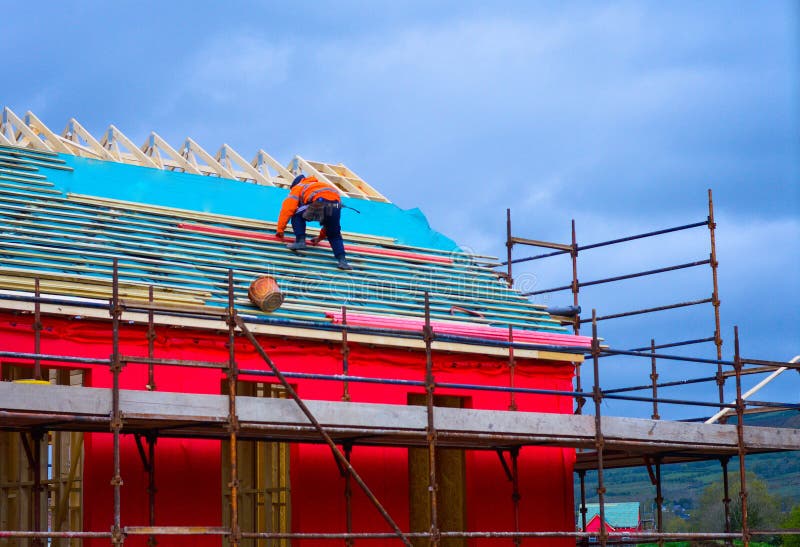 A worker placing wood on the sloped roof of a new house under construction. royalty free stock photo A worker placing wood on the sloped roof of a new house under construction. royalty free stock photo
